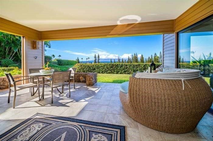 A patio with a table and chairs and a hot tub.