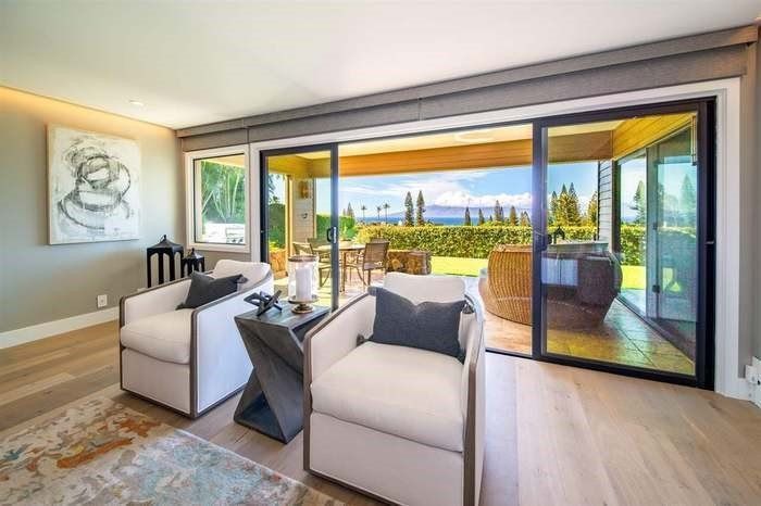 A living room with two chairs and a table with sliding glass doors leading to a patio.