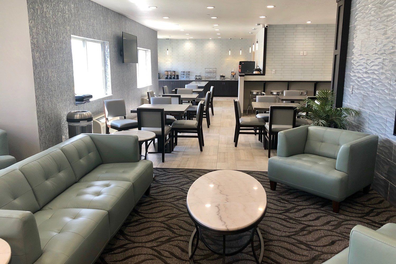 A hotel lobby with a couch , chairs , tables and a coffee table.
