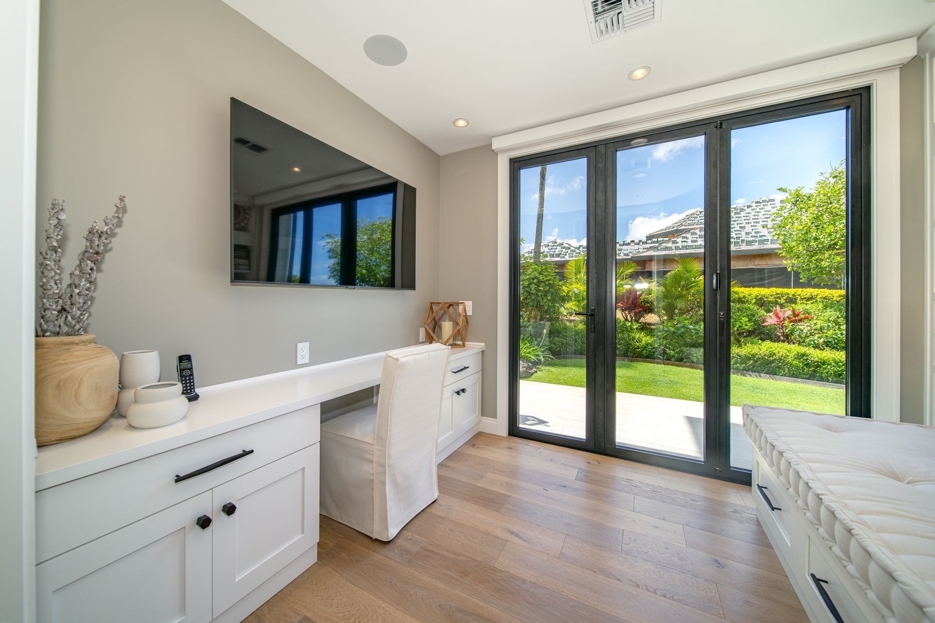 A room with a large flat screen tv on the wall and sliding glass doors.