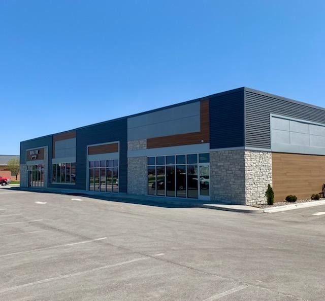 A large building with a lot of windows and a parking lot in front of it