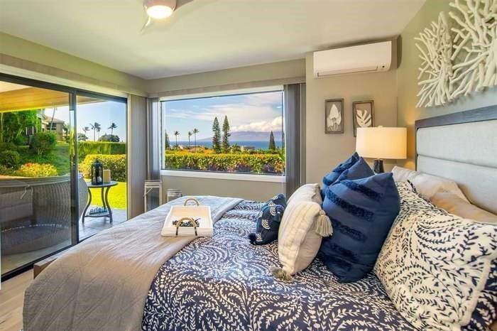 A bedroom with a large bed and a large window with a view of the ocean.