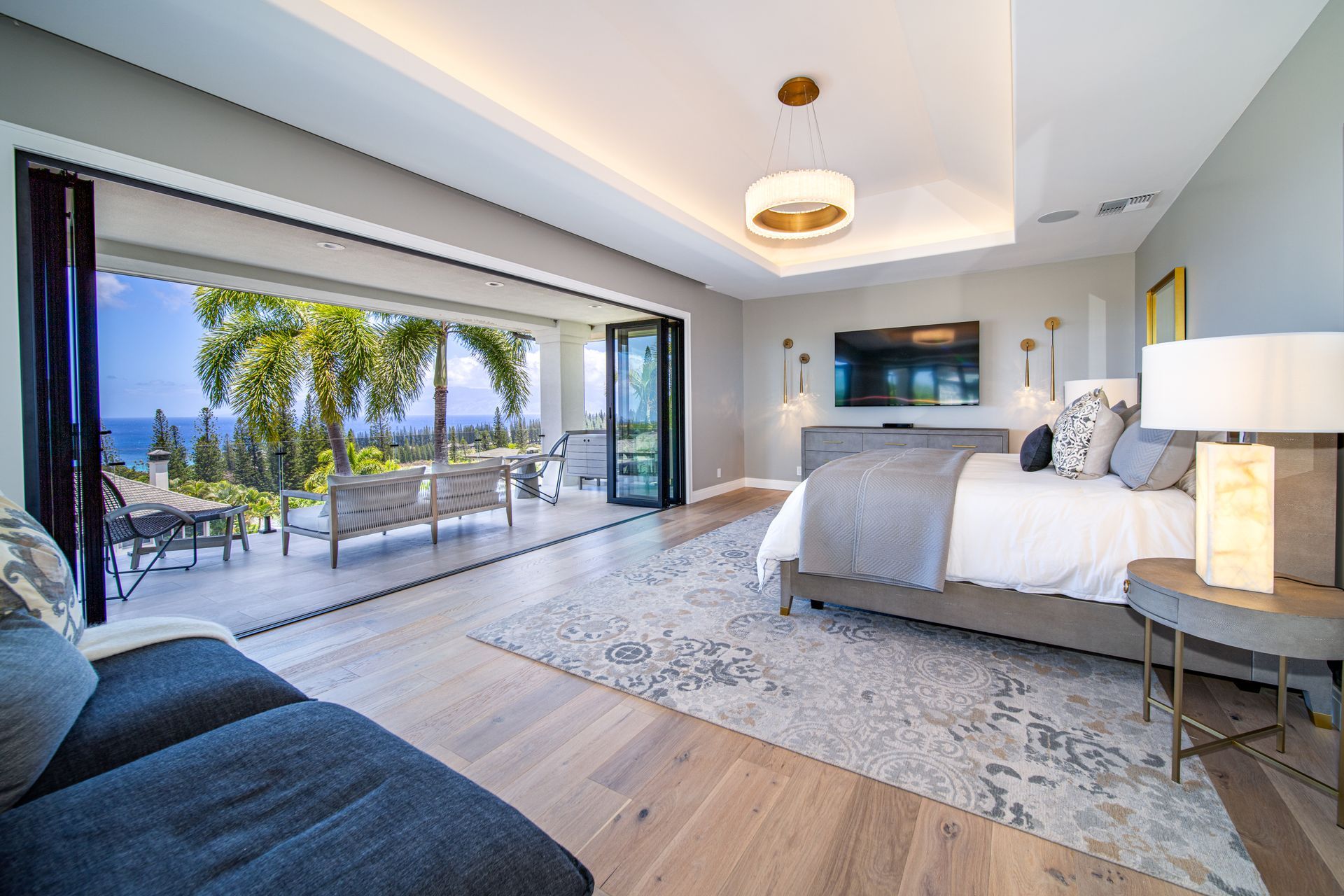 A bedroom with a large bed , couch , television and sliding glass doors.