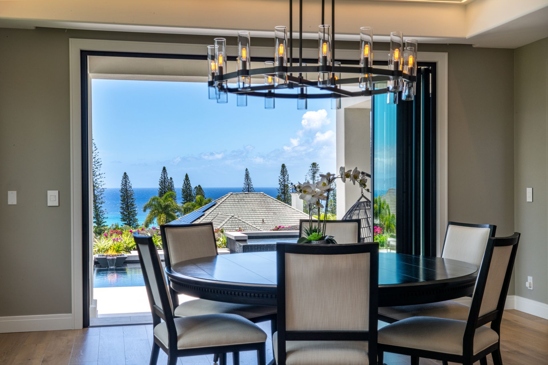 A dining room with a table and chairs and a view of the ocean.