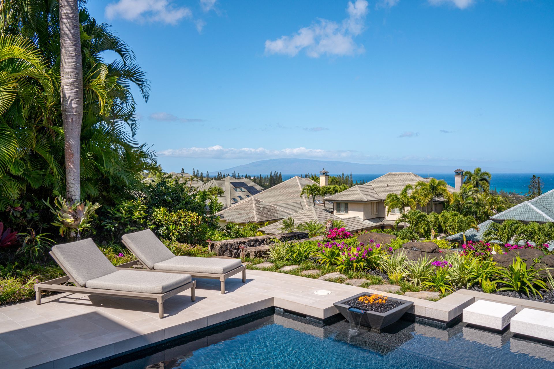 A swimming pool with a view of the ocean and a house in the background.