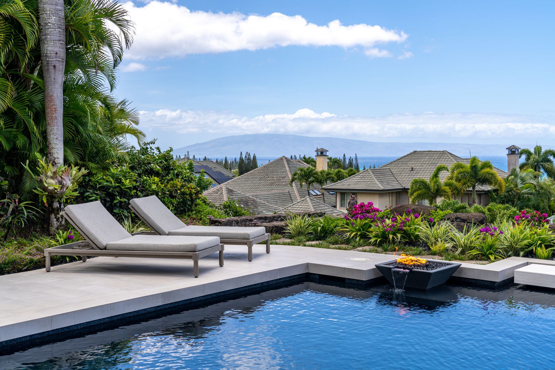 There are two lounge chairs next to a large swimming pool.