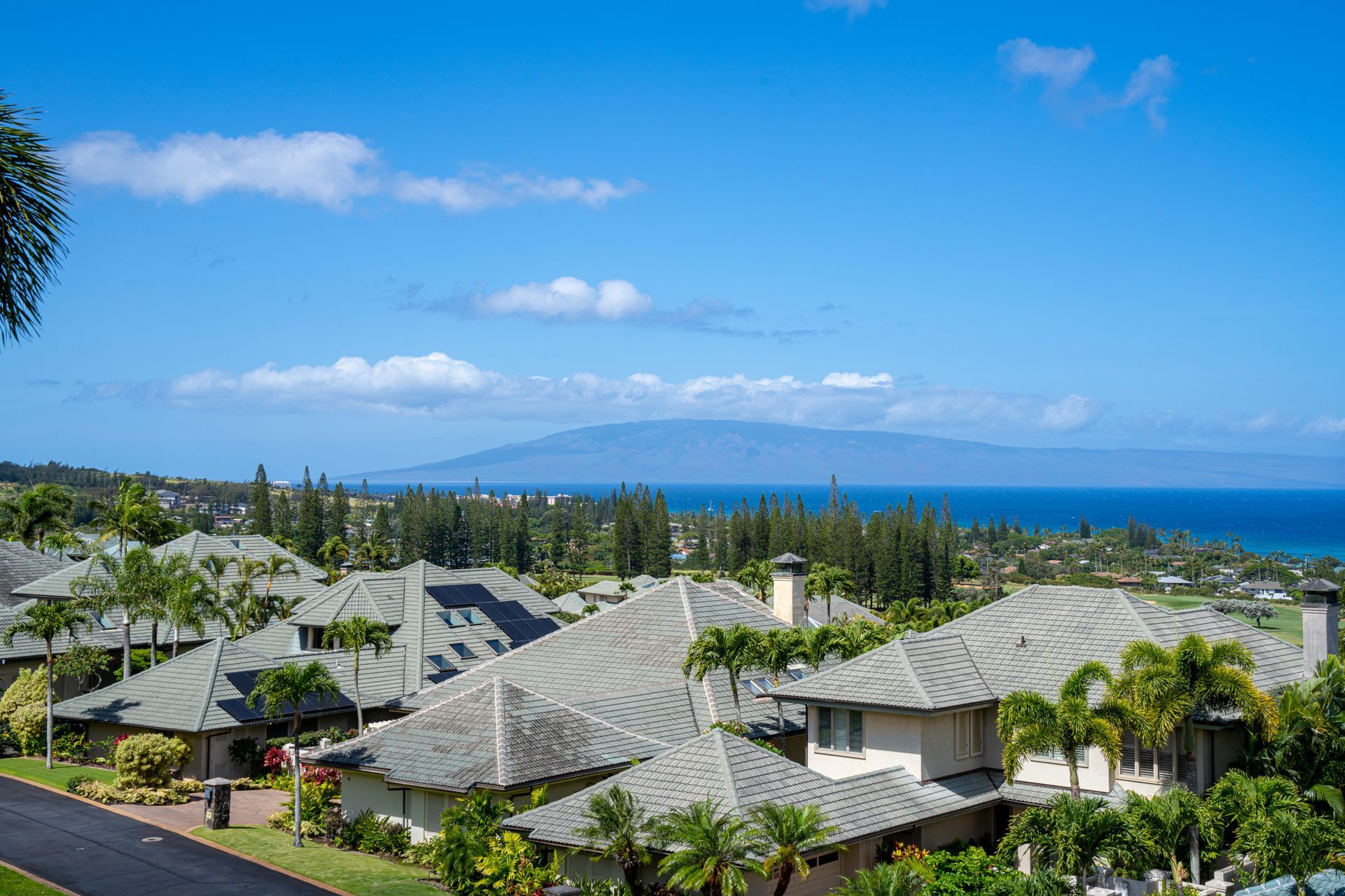 A row of houses with a view of the ocean and mountains in the background.