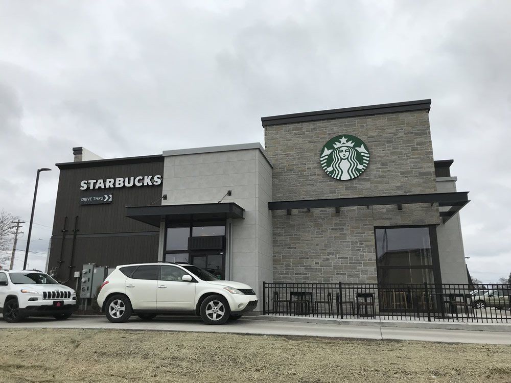 A white car is parked in front of a starbucks coffee shop.
