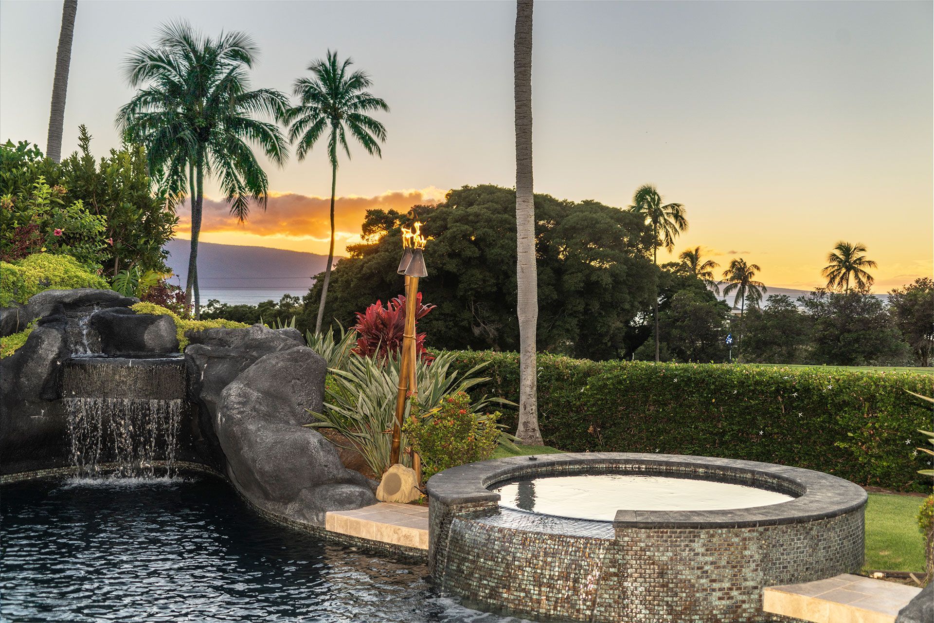 A hot tub with a waterfall and palm trees in the background