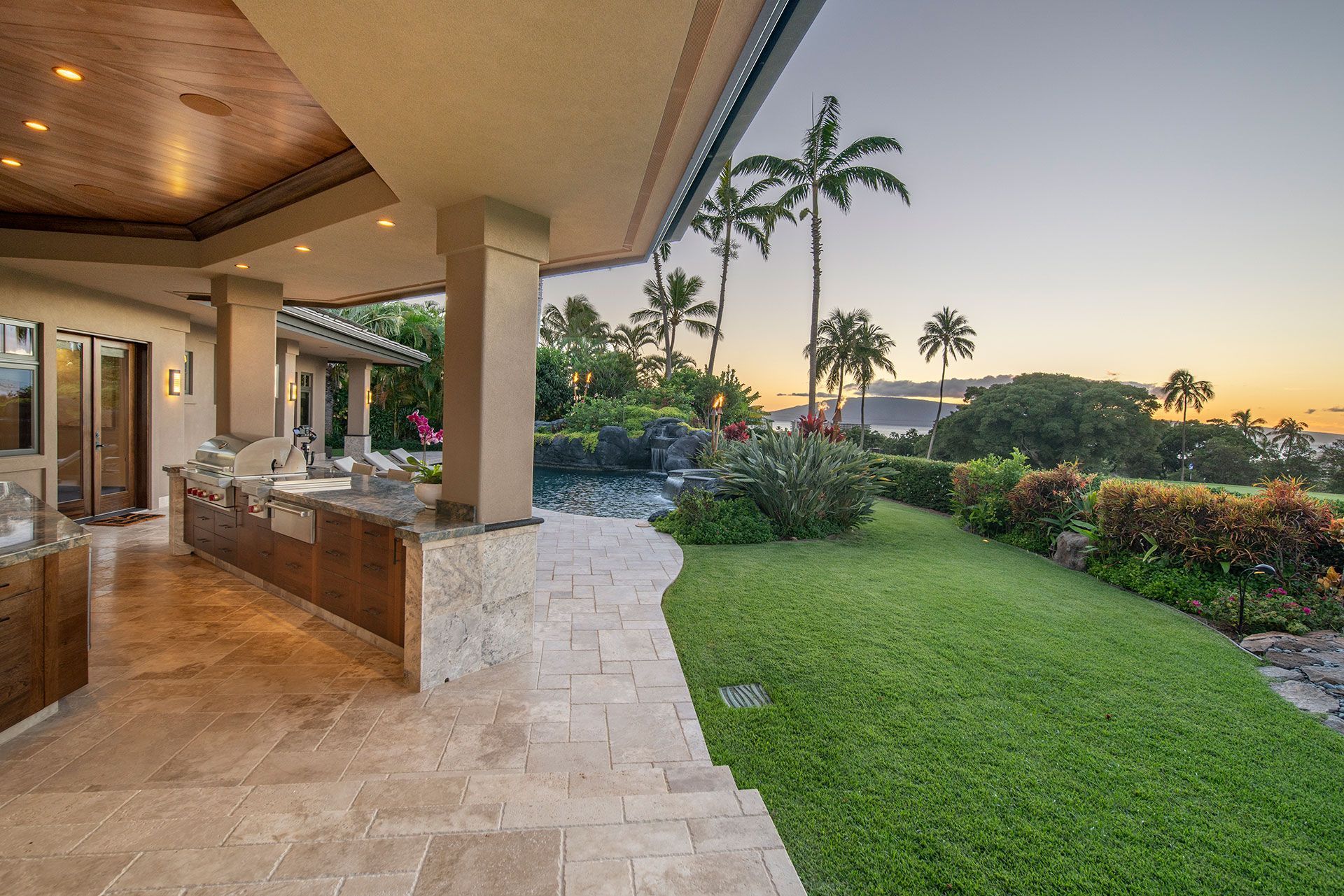 A large house with a lush green lawn and palm trees in the background