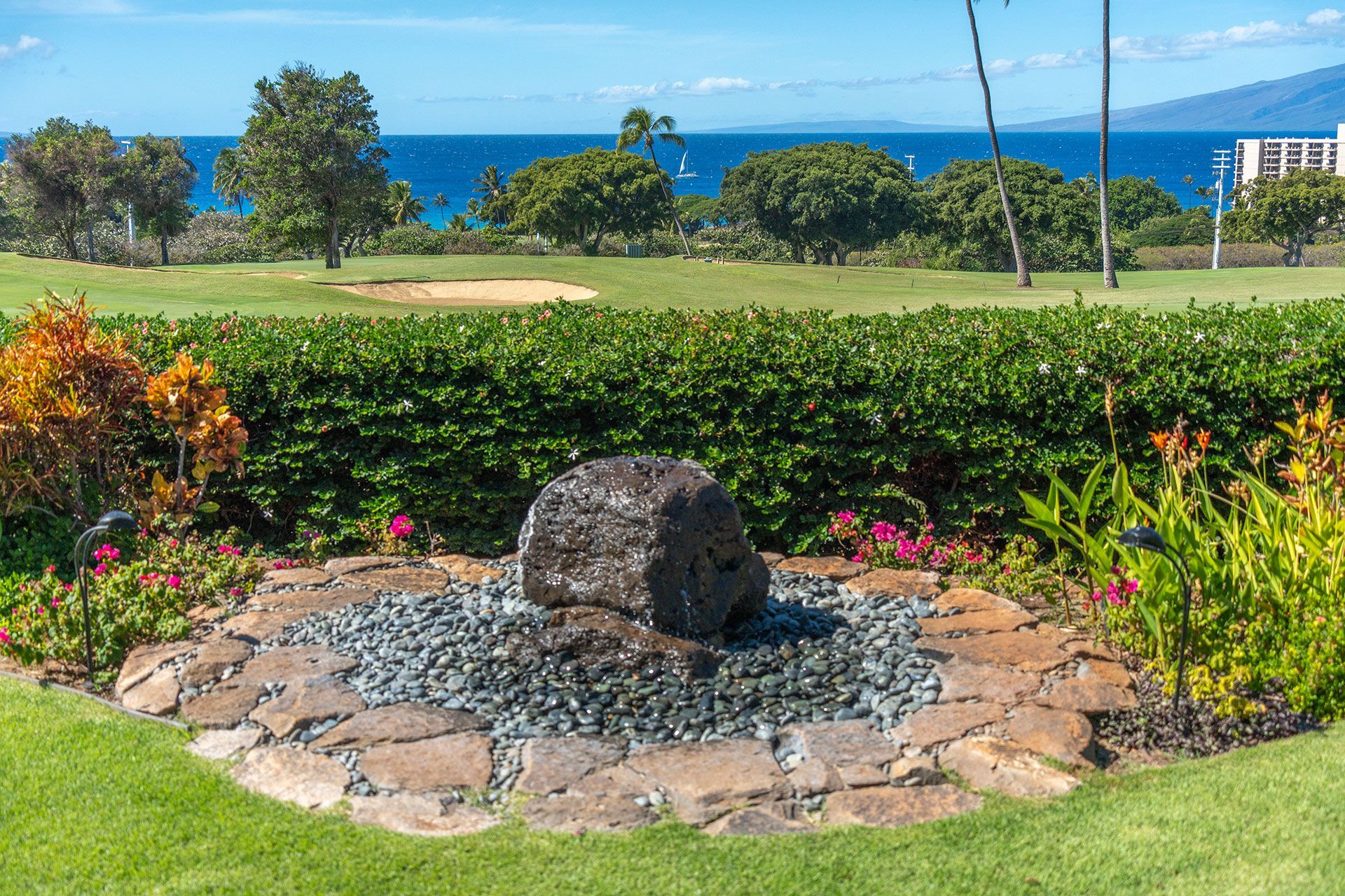 A rock in the middle of a garden with a view of the ocean