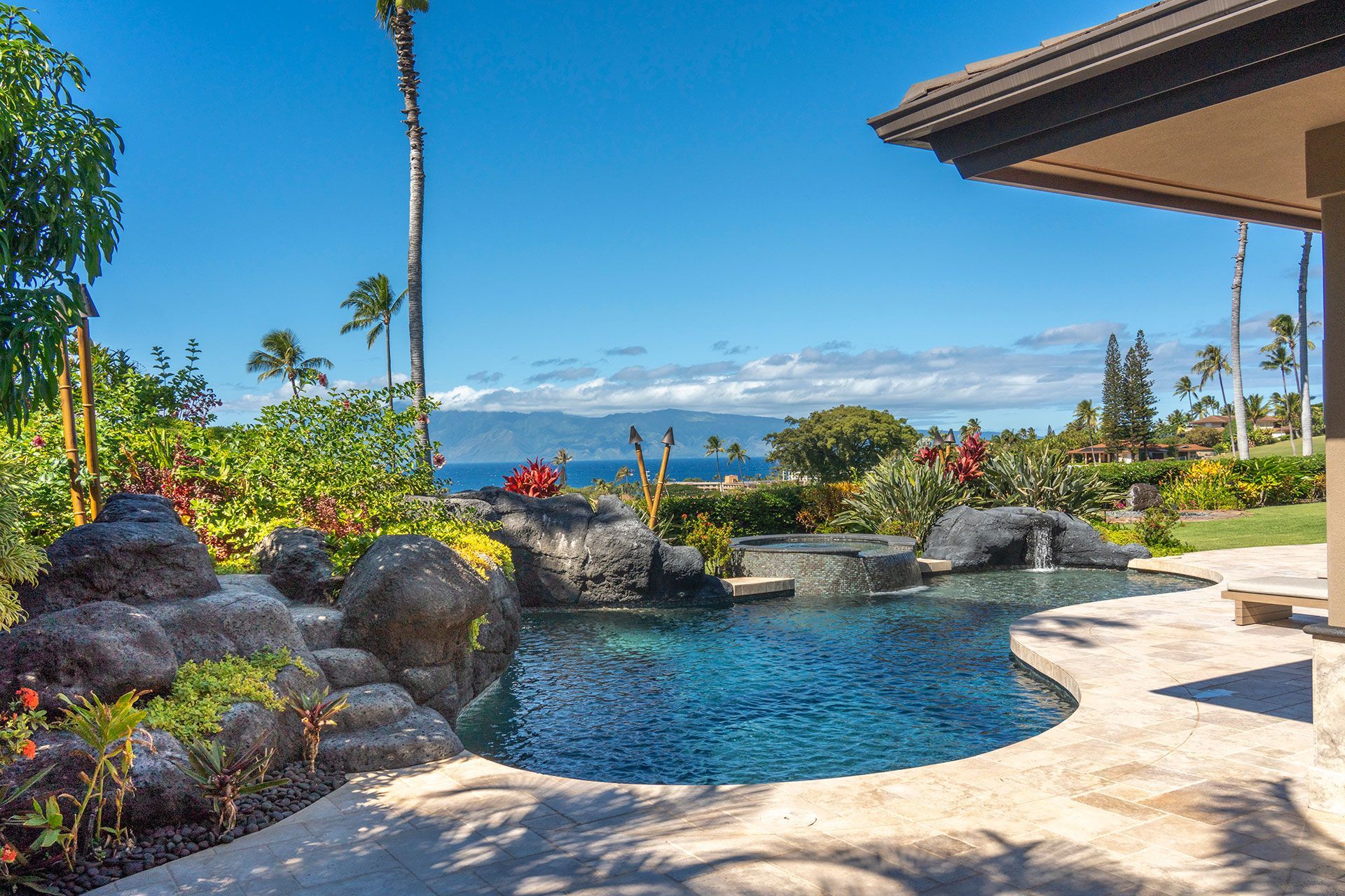 A large swimming pool in the backyard of a house with a view of the ocean