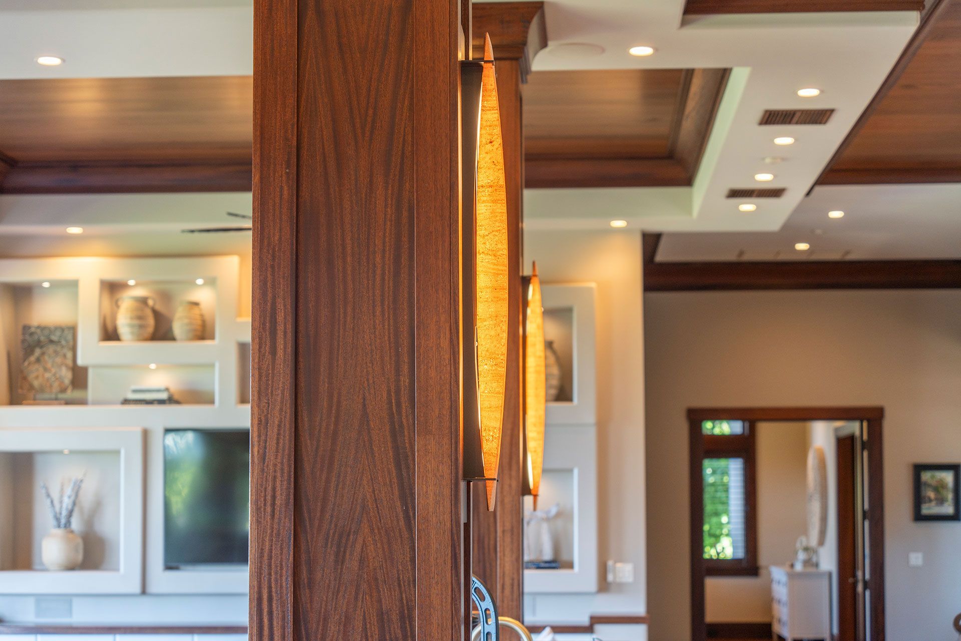 A wooden door is open to a living room with a television on the wall