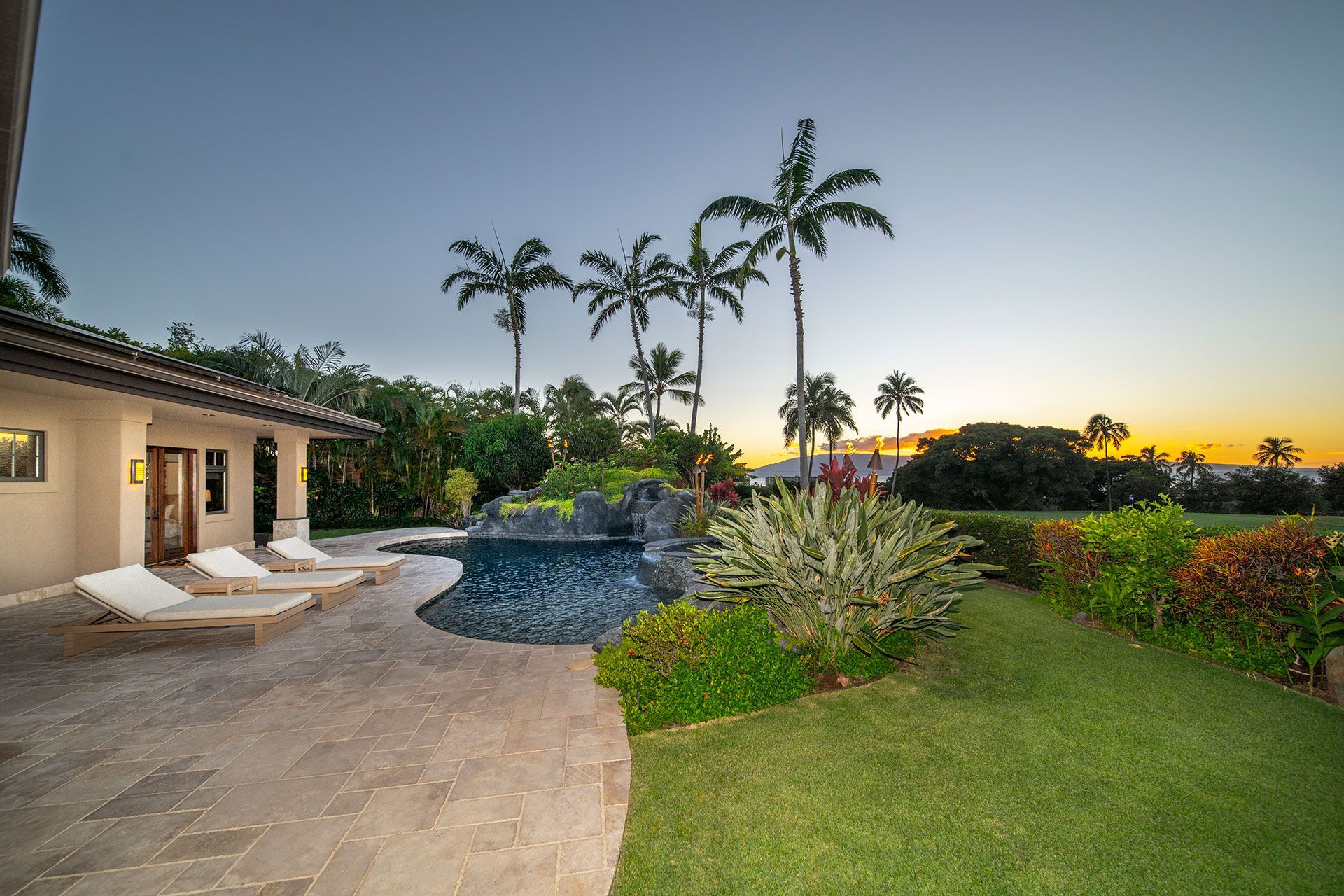 There is a large swimming pool in the backyard of a house