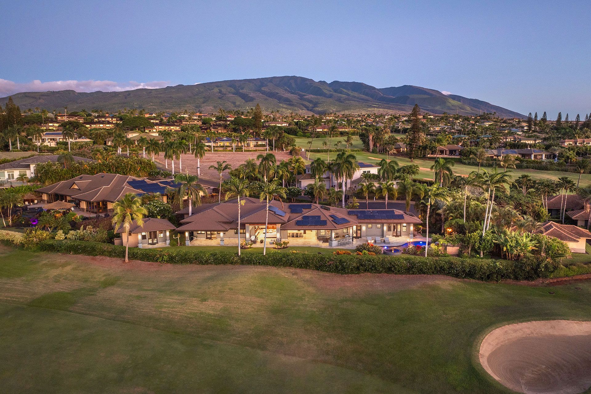 An aerial view of a house and a golf course with mountains in the background
