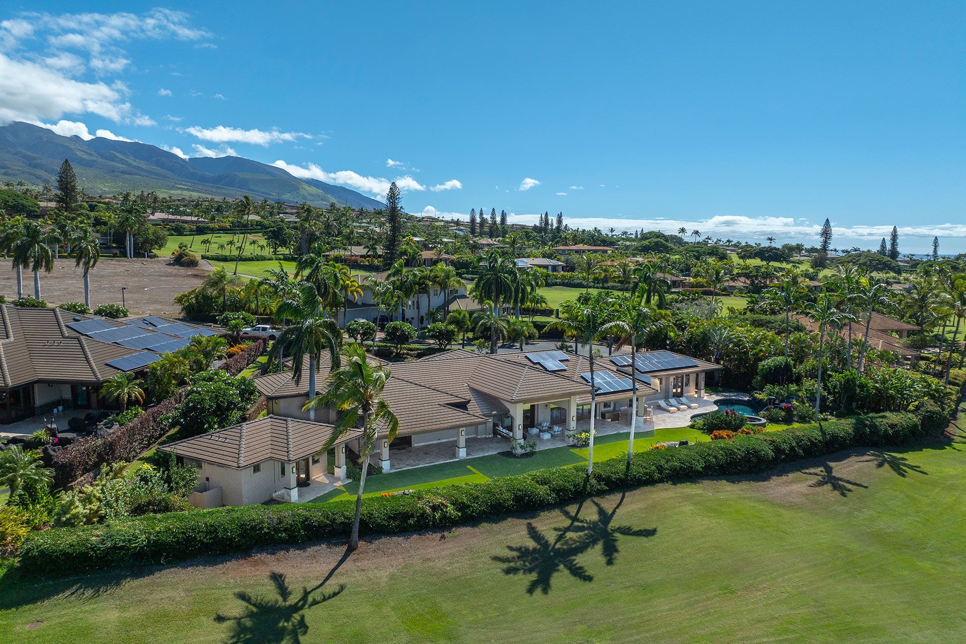 An aerial view of a house surrounded by palm trees and mountains