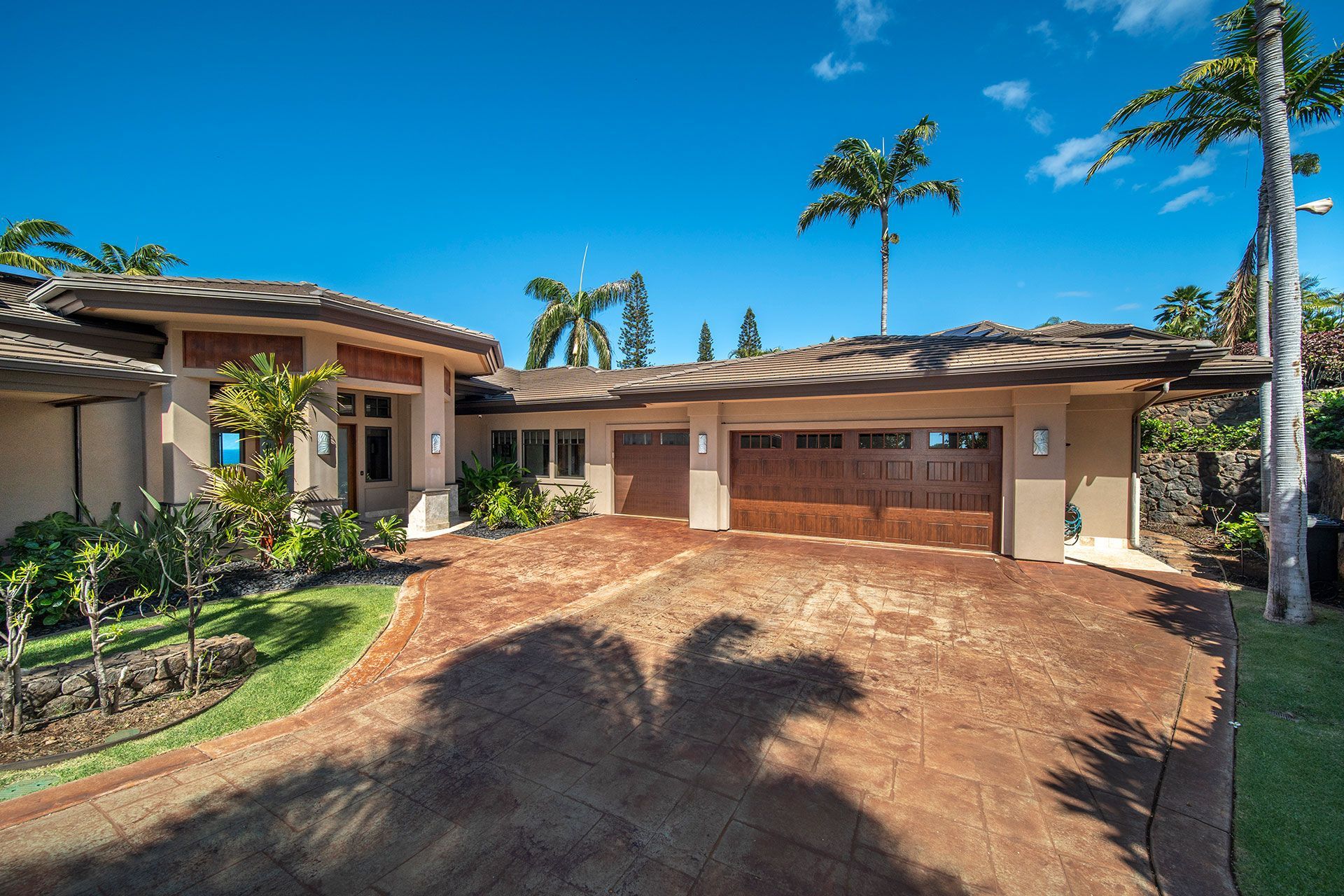 The shadow of a palm tree is cast on the driveway of a house
