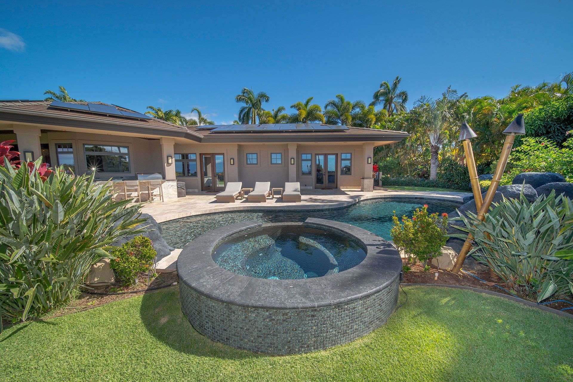 A large house with a swimming pool and a hot tub in front of it.