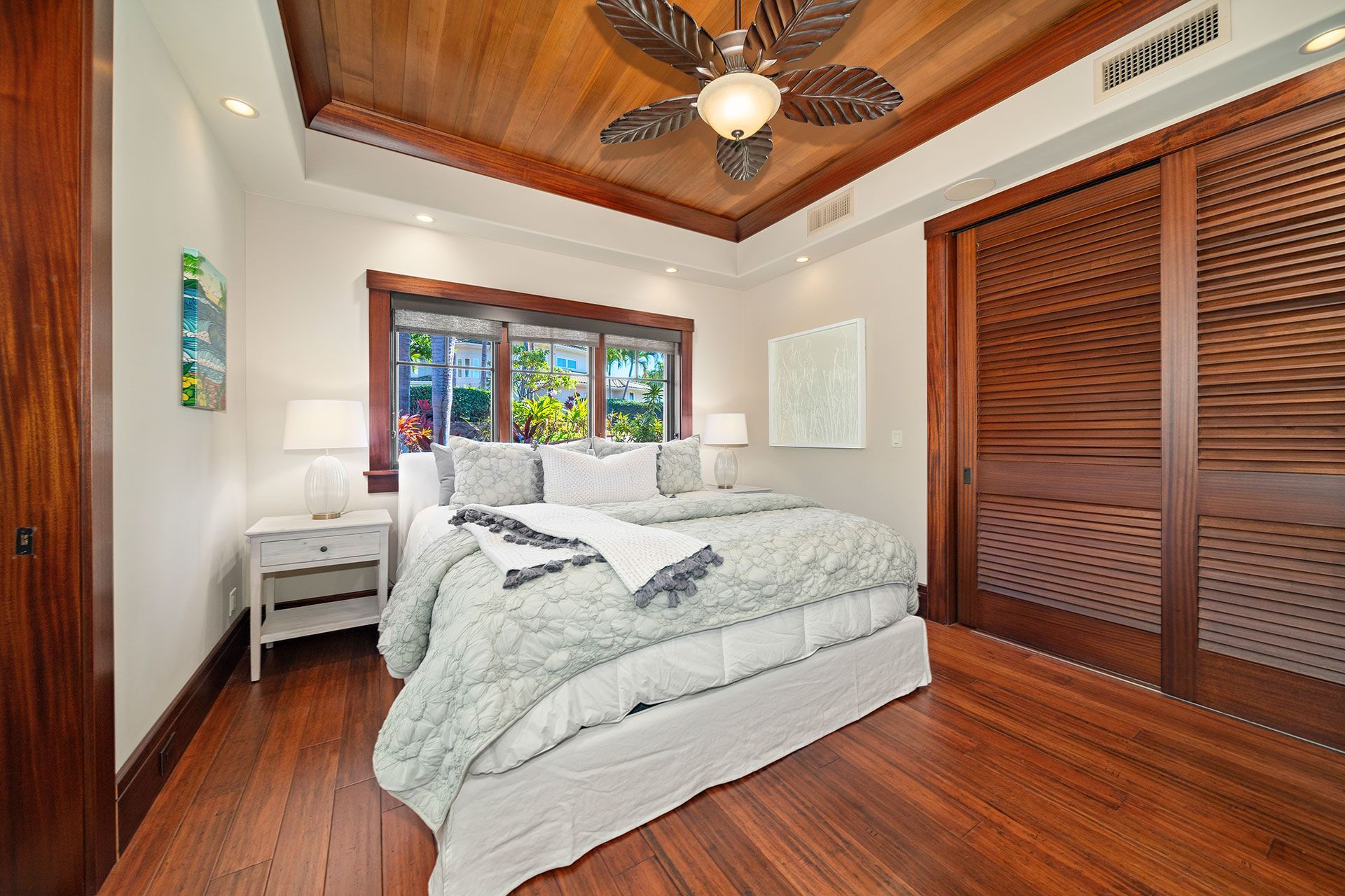 A bedroom with a king size bed and a ceiling fan
