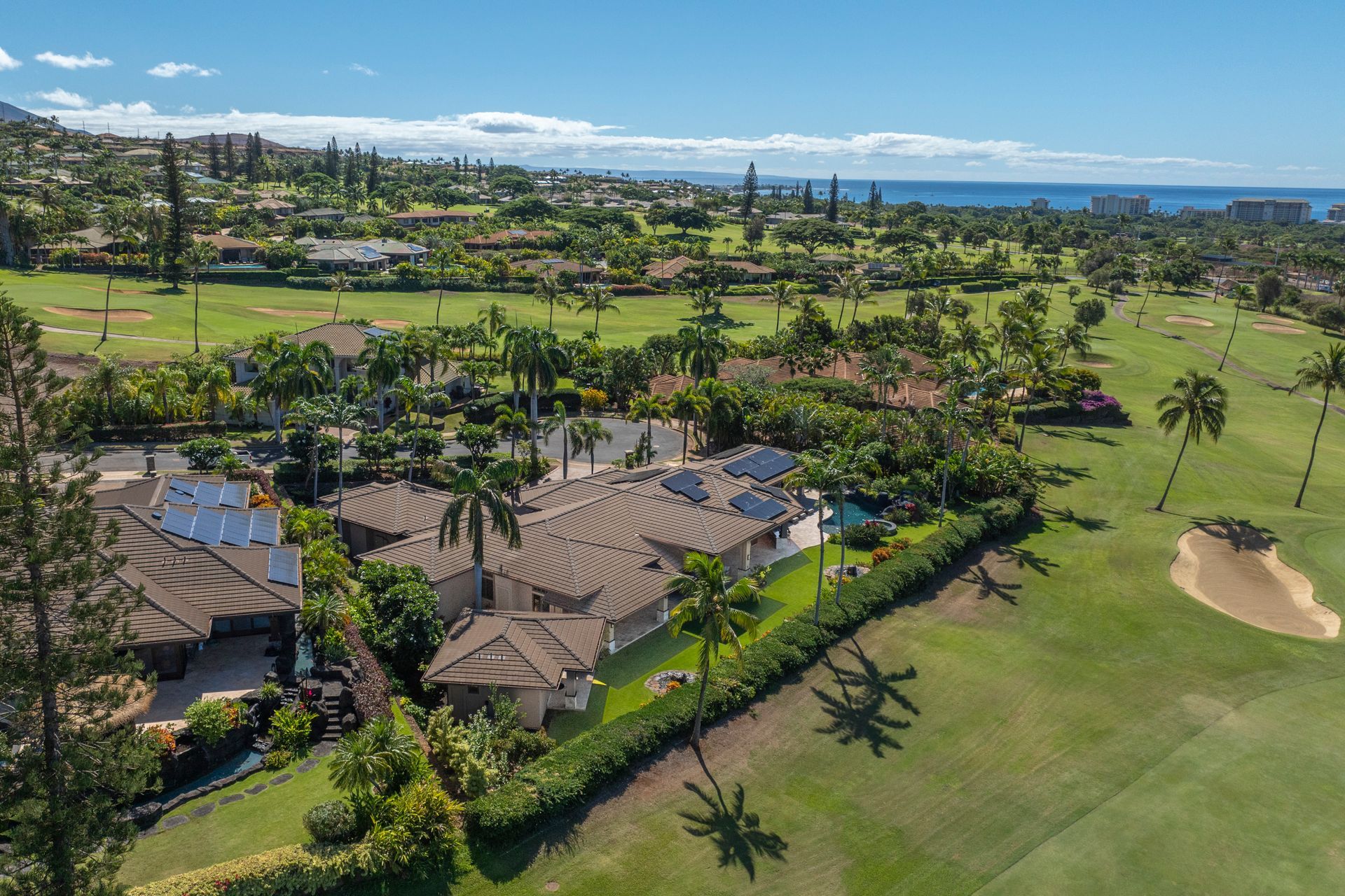 An aerial view of a residential area with a golf course in the background.