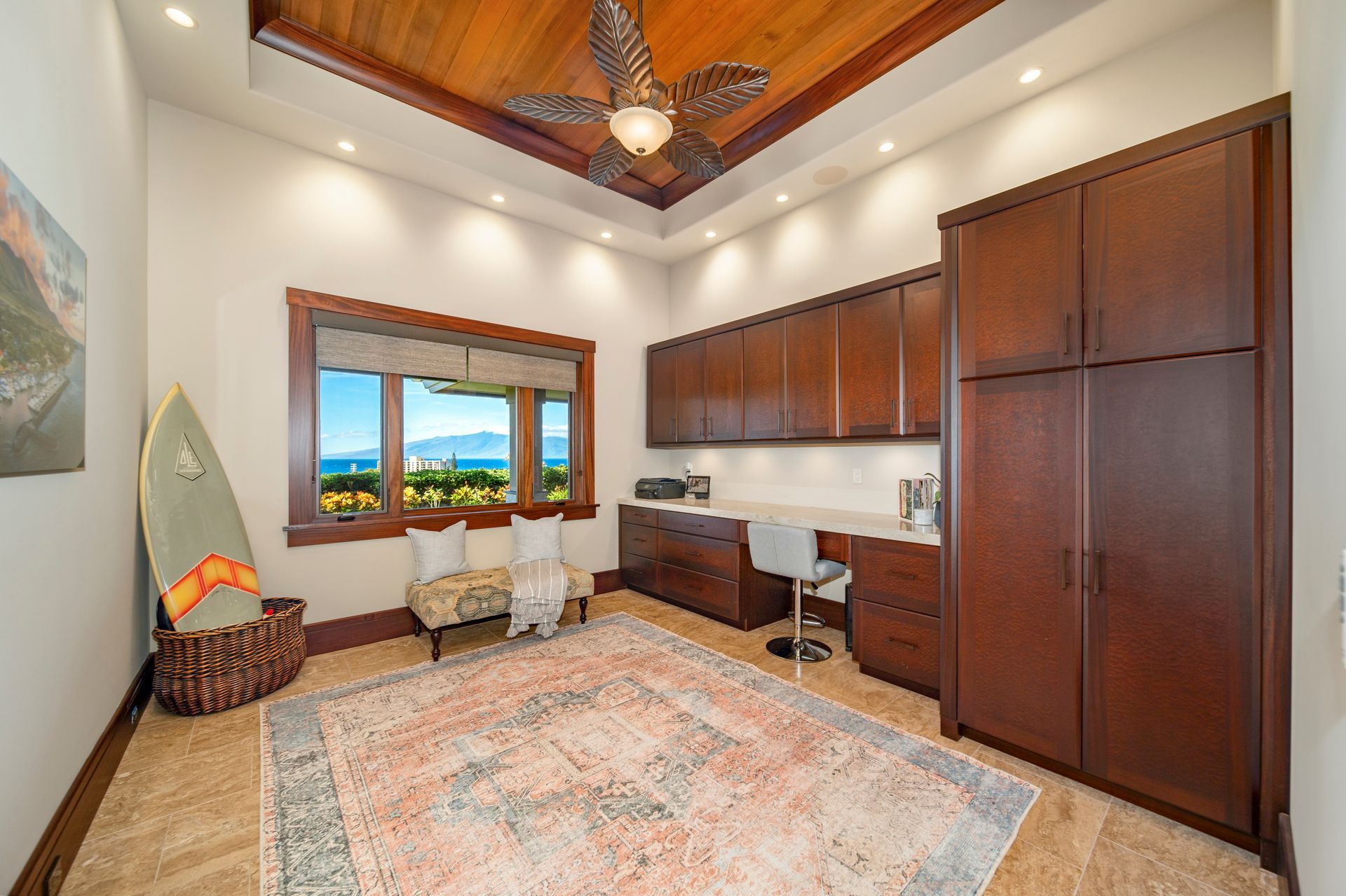 A room with a ceiling fan and a surfboard on the wall.