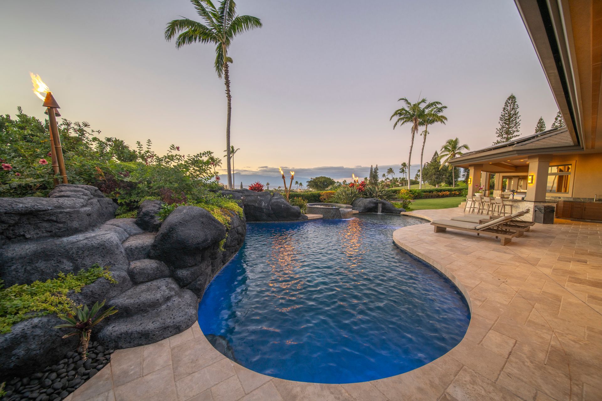 There is a large swimming pool in the backyard of a house.