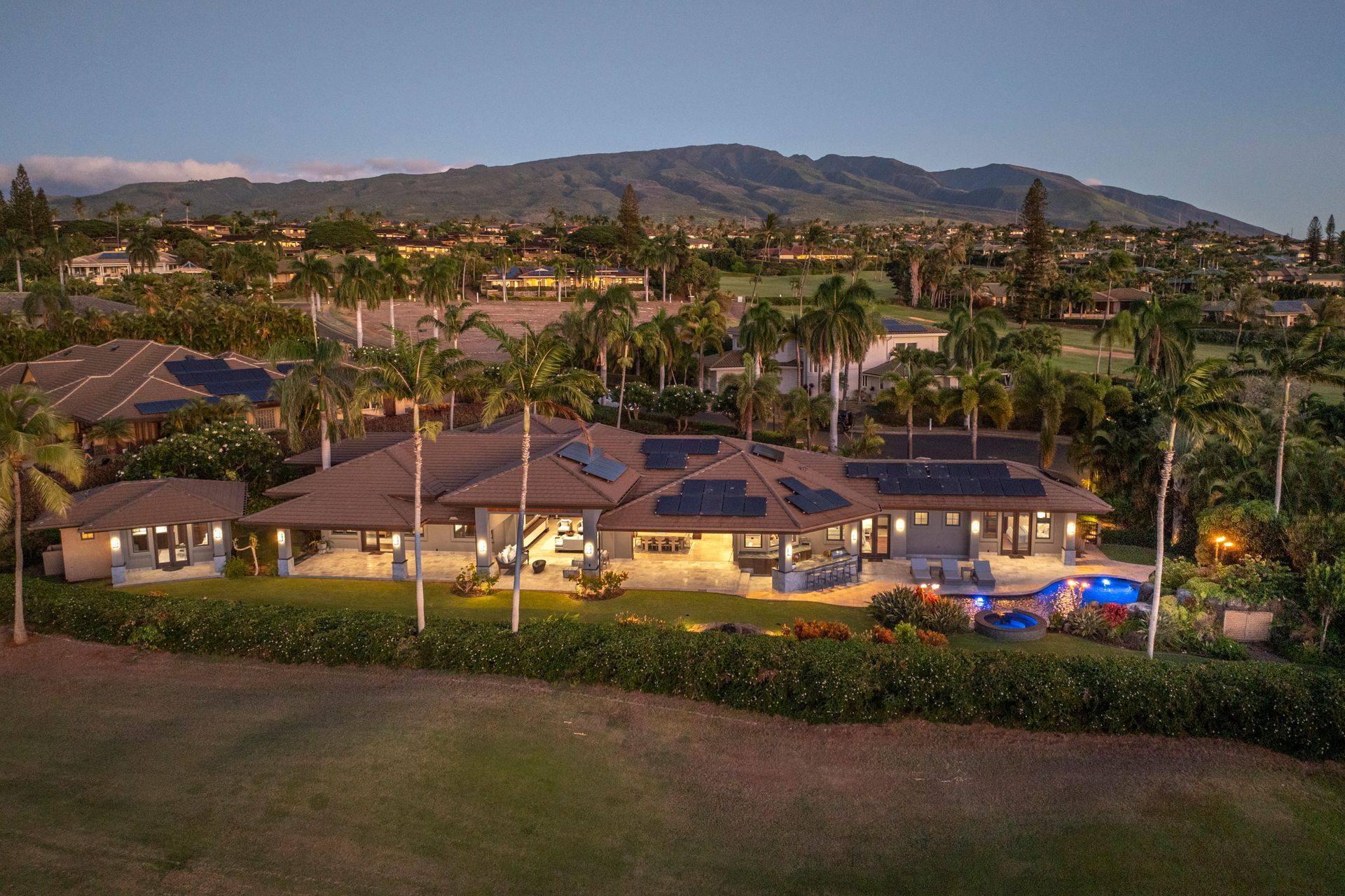 An aerial view of a large house with a pool and mountains in the background.