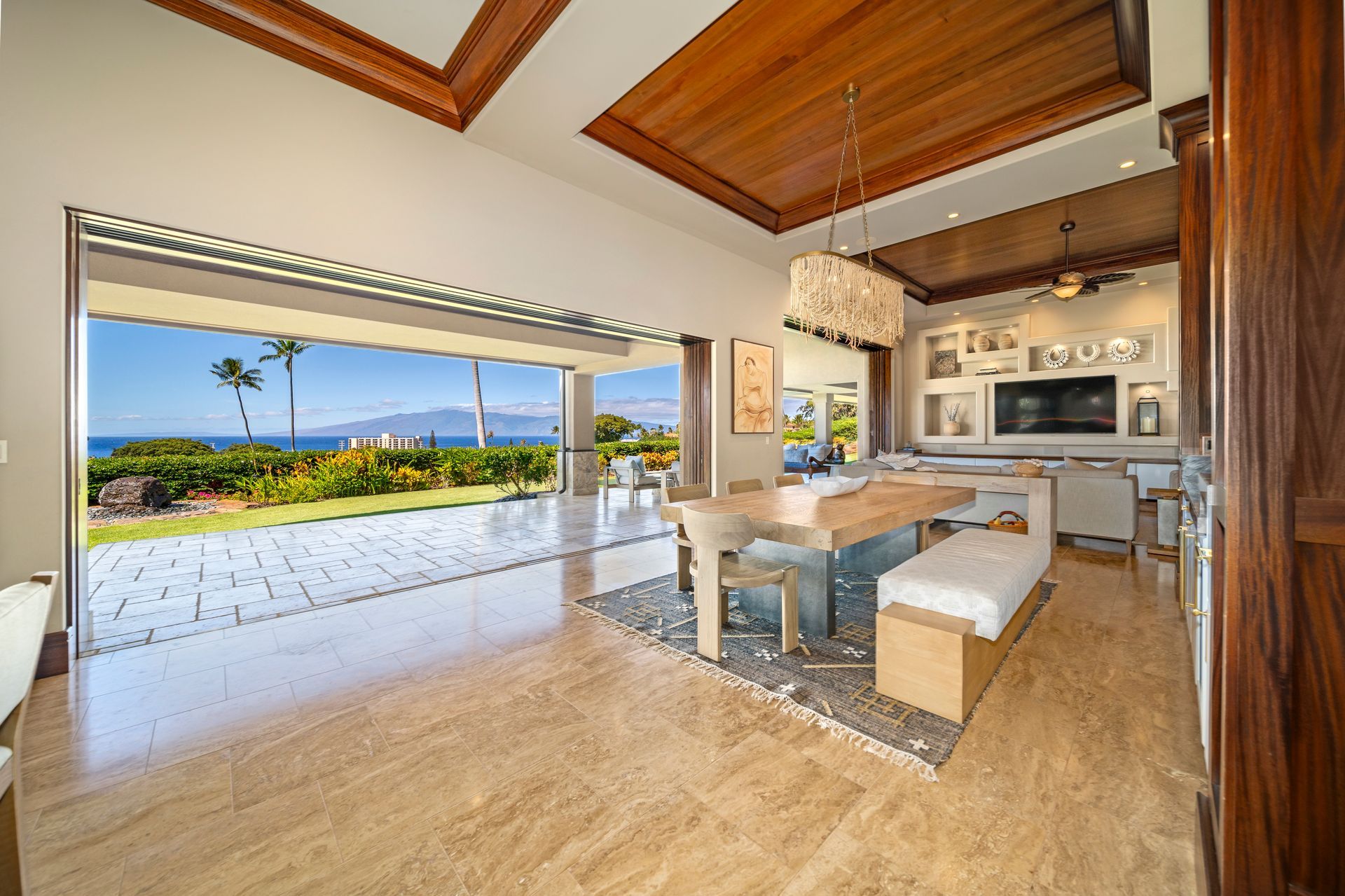 A dining room with a table and chairs and a view of the ocean.