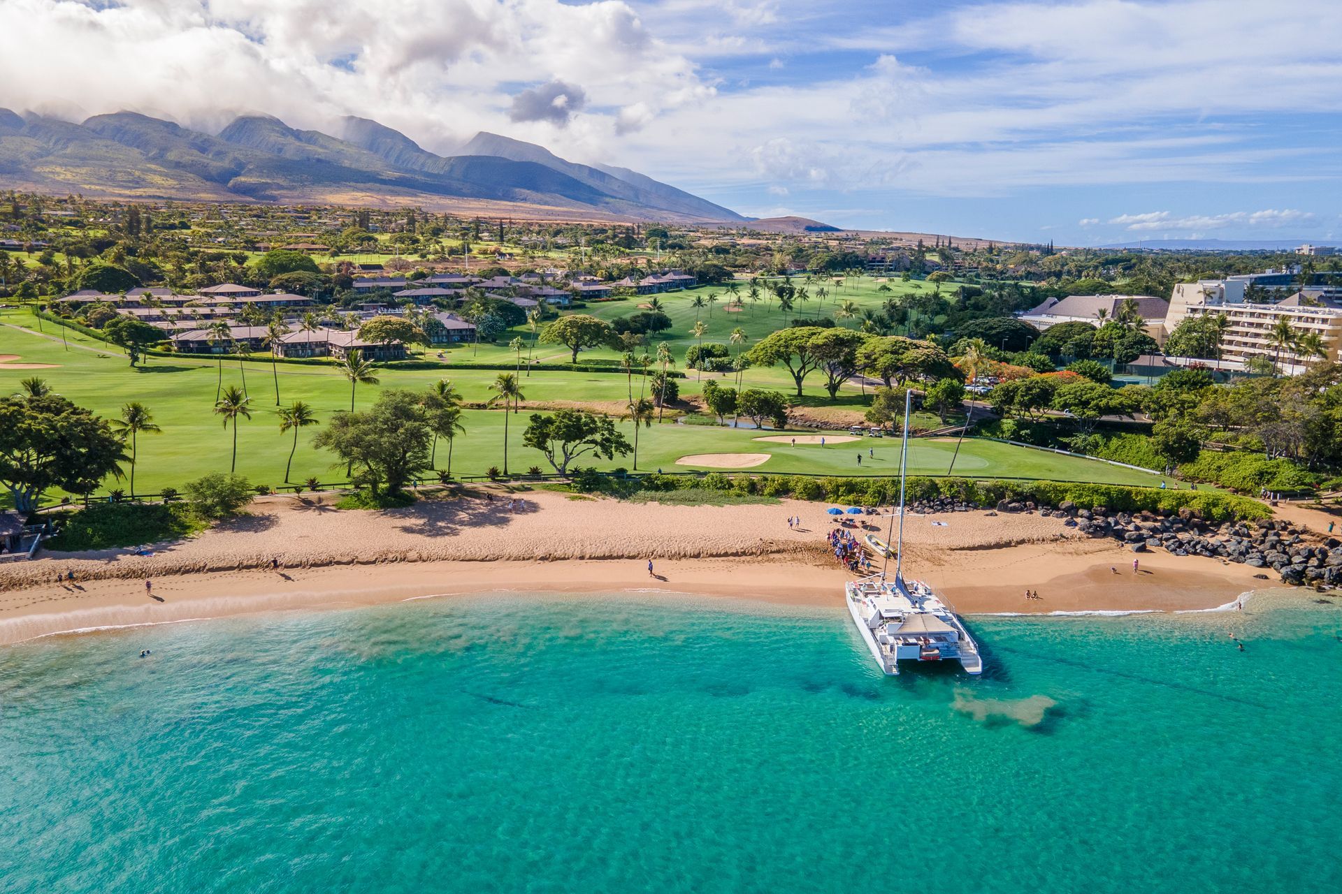 An aerial view of a beach with a boat in the water.