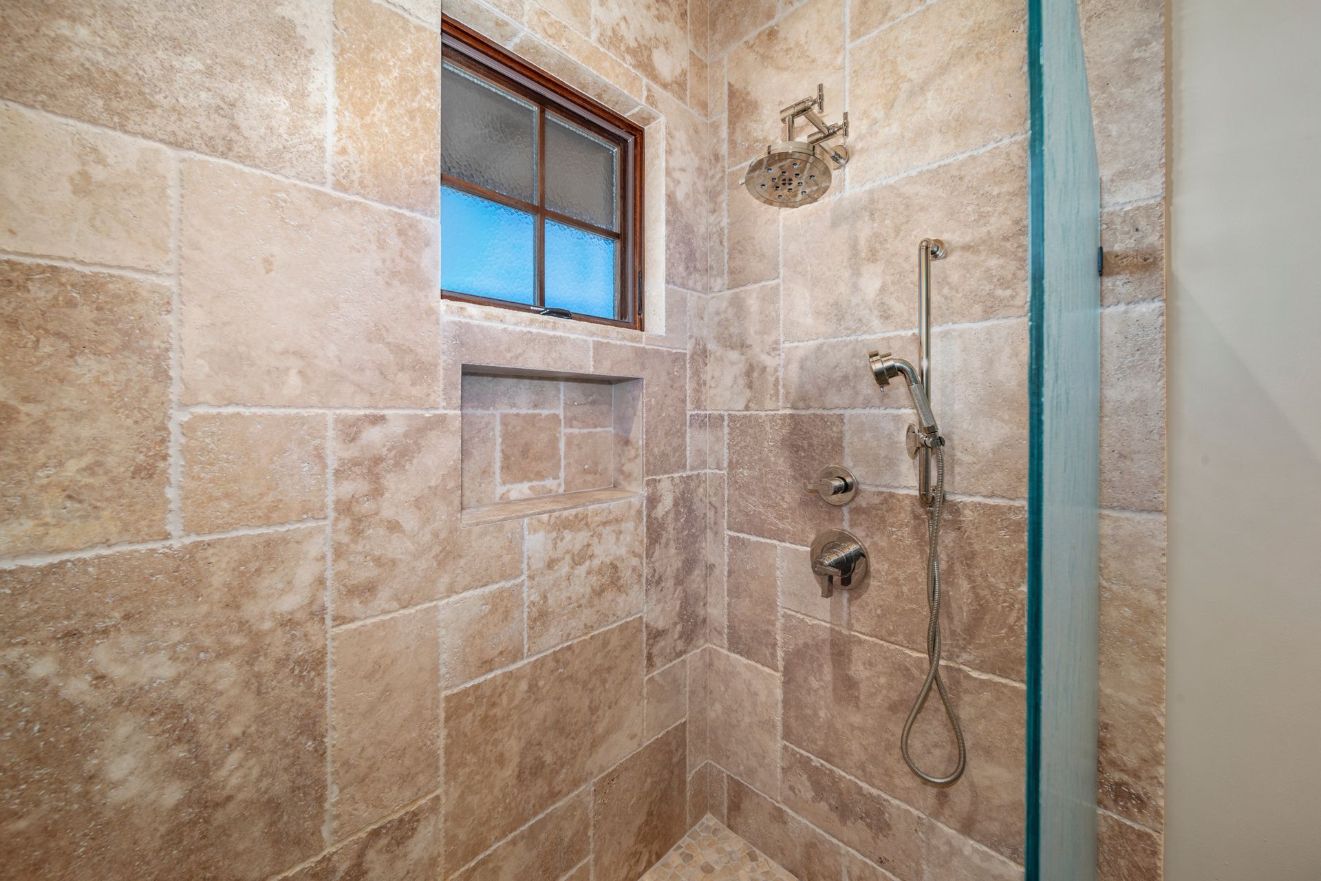 A bathroom with a walk in shower and a window.