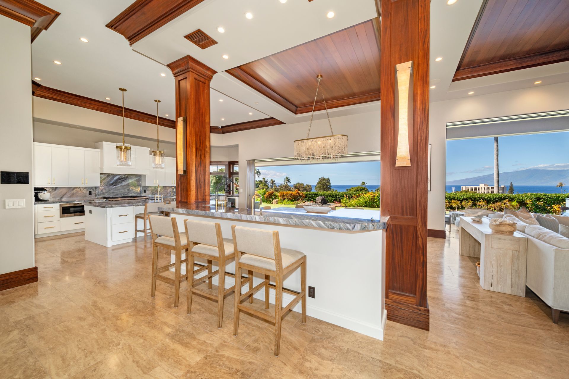 A kitchen with a bar and stools and a view of the ocean.
