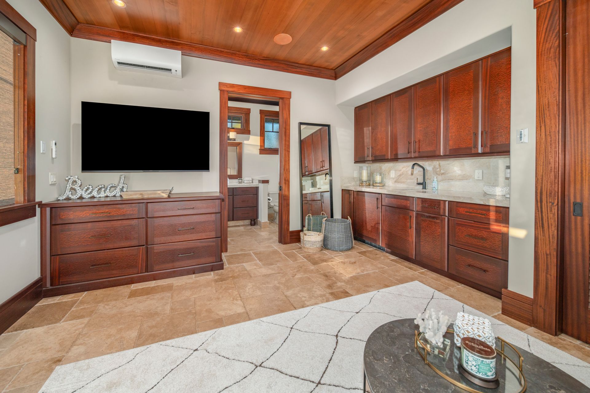 A living room with a flat screen tv and wooden cabinets.