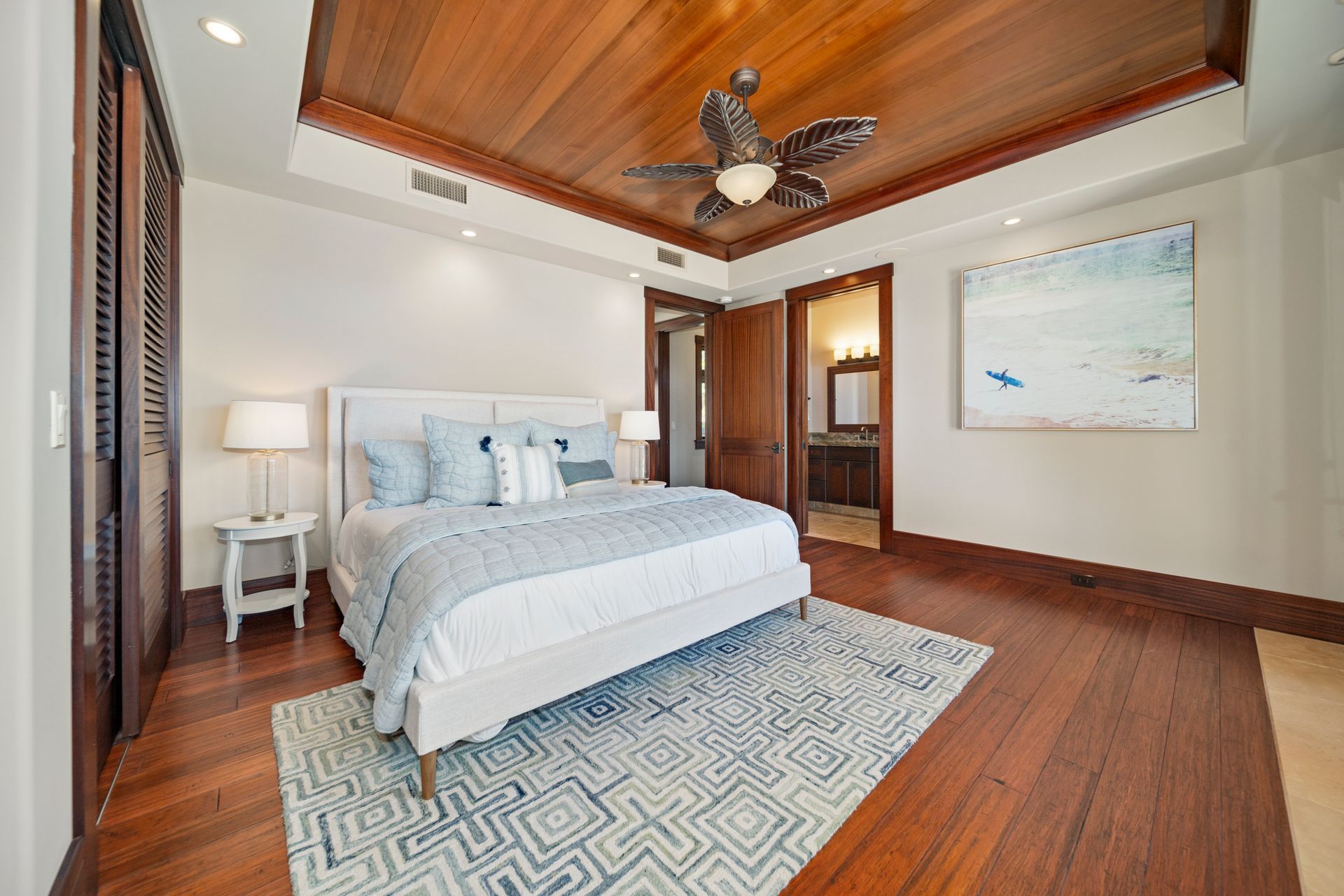 A bedroom with a king size bed and a ceiling fan.