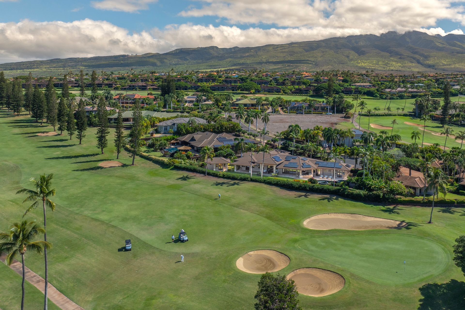 An aerial view of a golf course with mountains in the background.