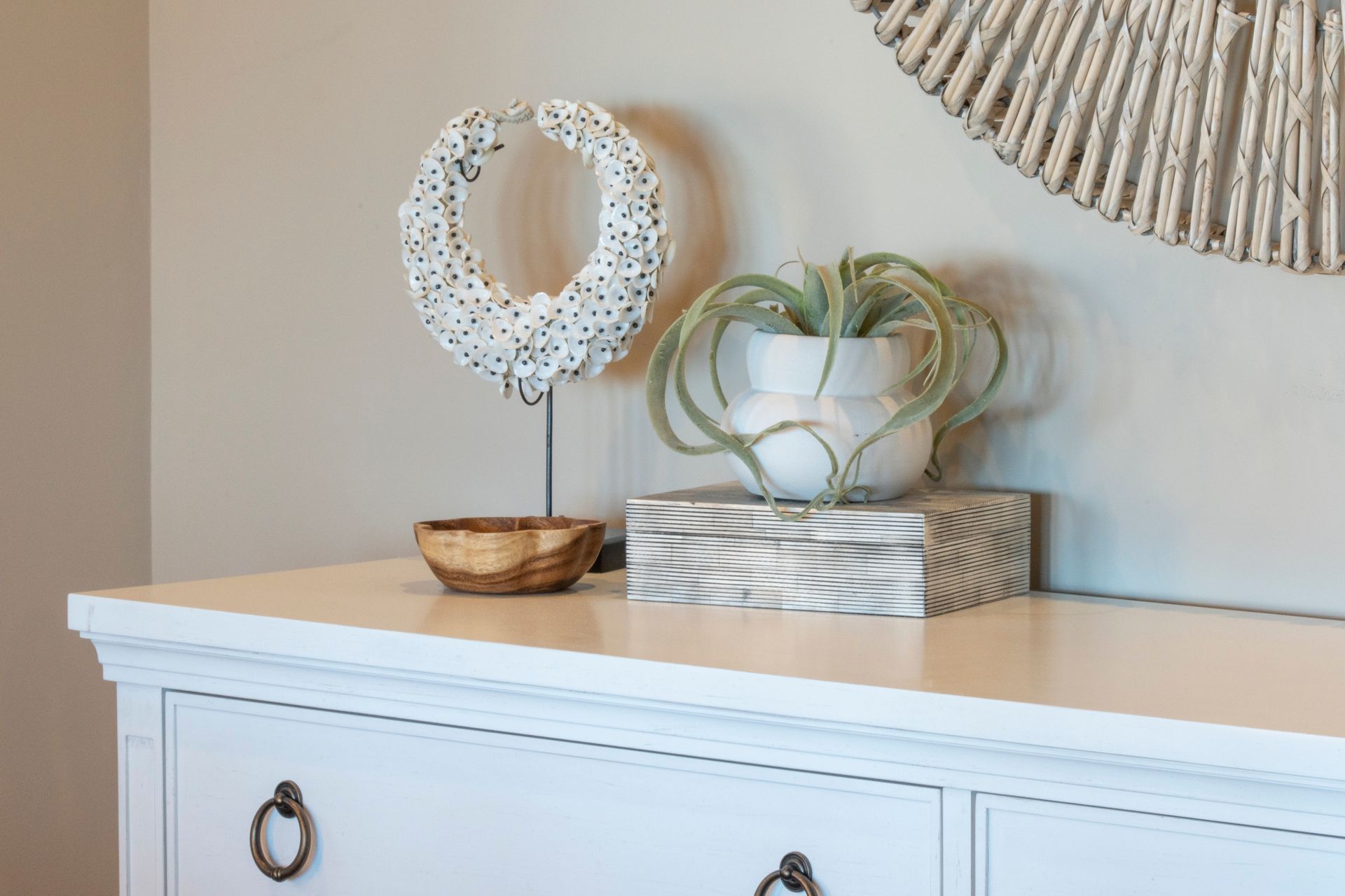 A white dresser with a potted plant on top of it.