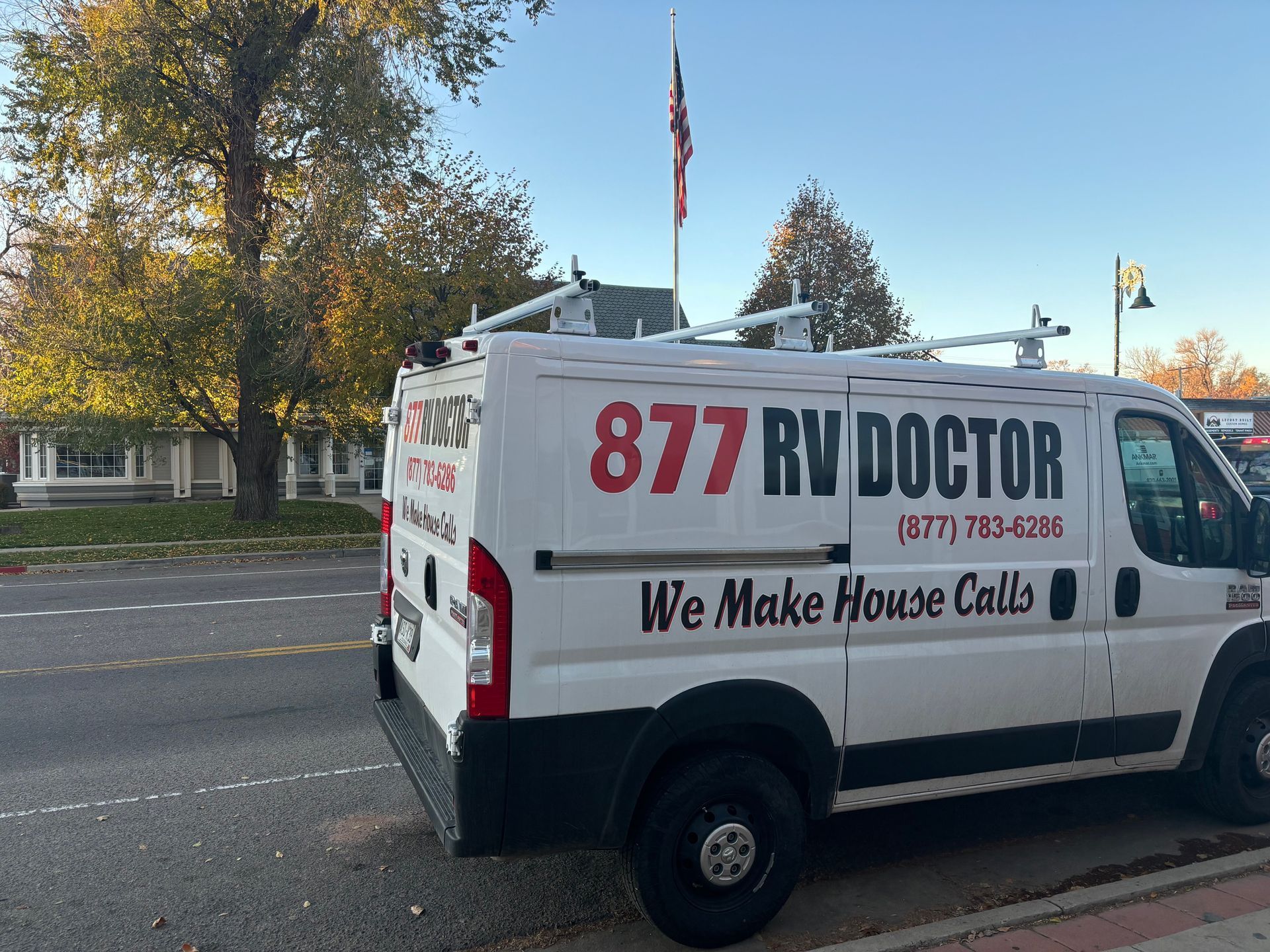 RV Doctor service van with large “877 RV DOCTOR” branding parked on a street near trees.