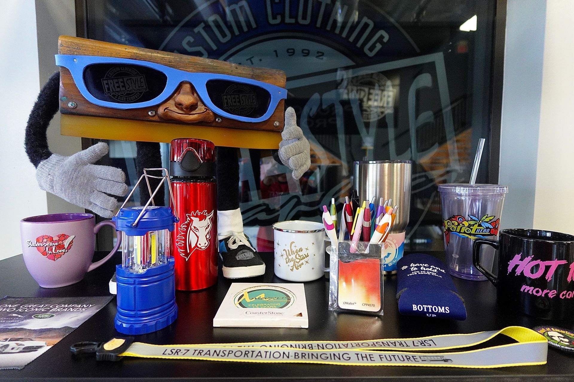 A table with a bunch of items on it and a sign that says custom clothing