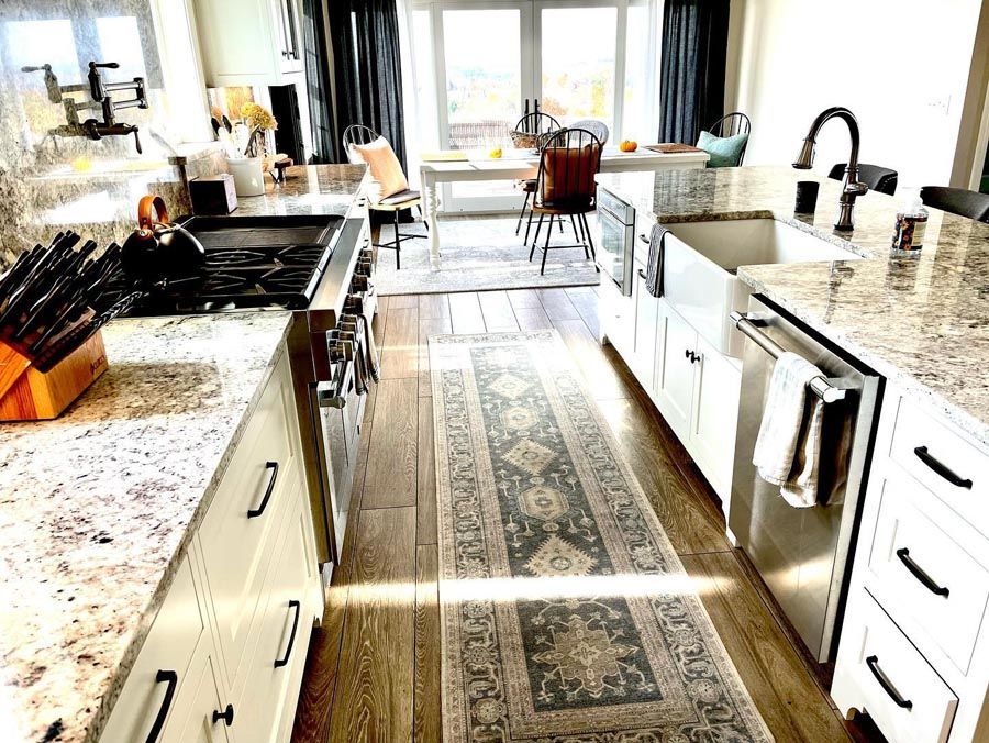 Modern kitchen with granite countertops, white cabinets, and a runner rug.
