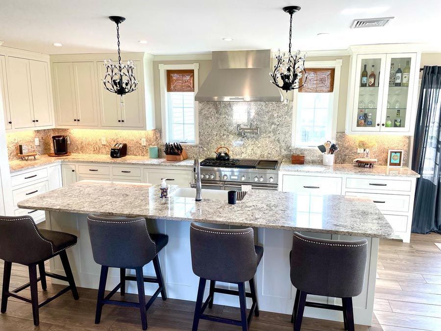 Kitchen with granite countertops, white cabinets, and island with bar stools.