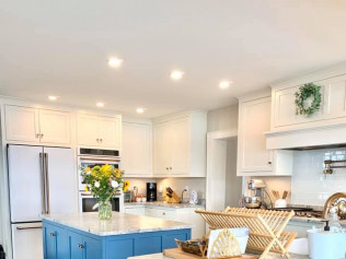 White kitchen with blue island, stainless steel appliances, and a flower bouquet.