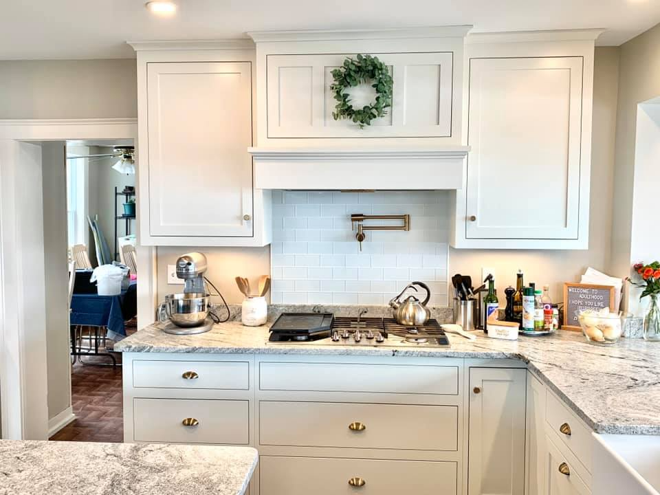 White kitchen with granite countertops, light cabinets, and a gas stove. A small wreath hangs above the stove.