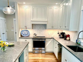 White kitchen with gray countertops, stainless steel stove, and light wood floors.
