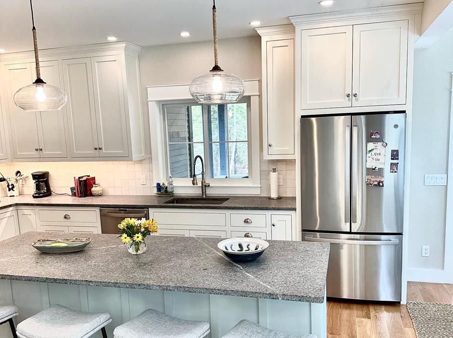 Kitchen with white cabinets, stainless steel refrigerator, and gray countertops.