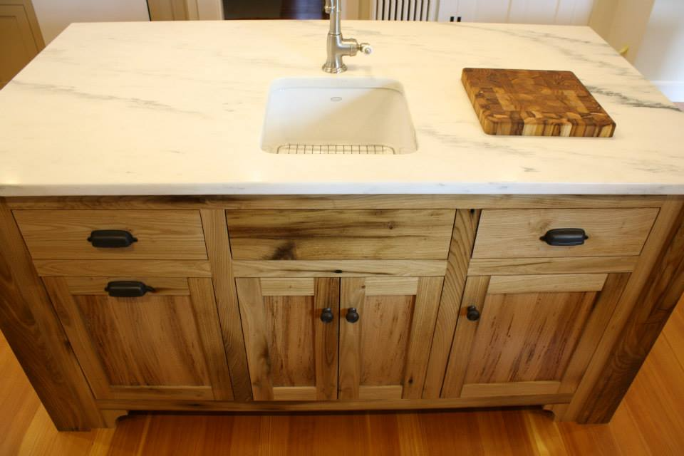 Wooden kitchen island with marble countertop, sink, and butcher block.