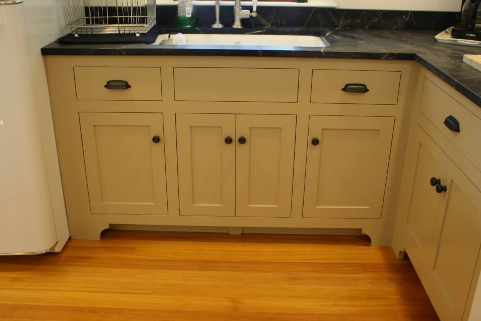 Kitchen cabinets with sink and black countertop, light yellow color, wood floor.