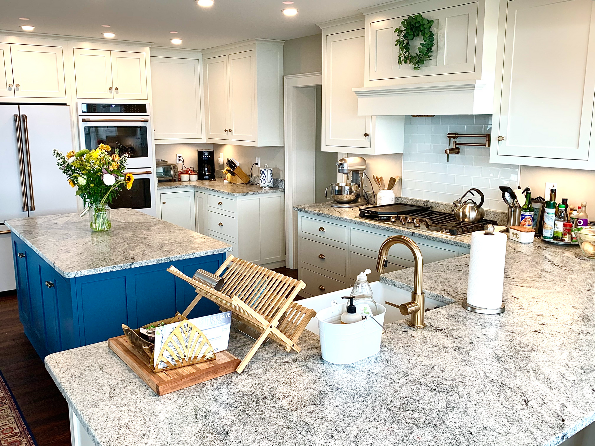 Bright kitchen with white cabinets, granite countertops, and a blue island.