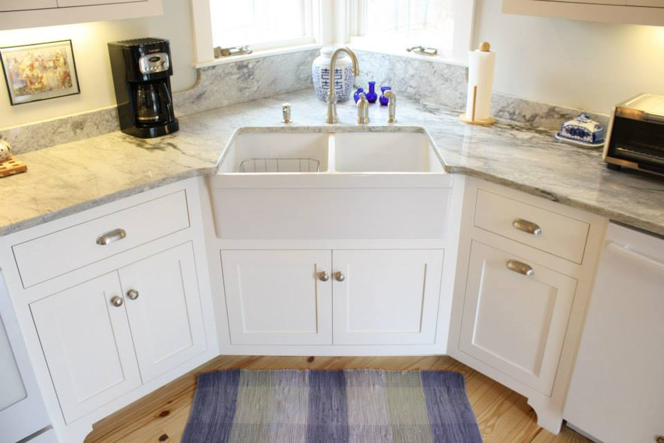 White farmhouse kitchen sink with granite countertops and white cabinets.
