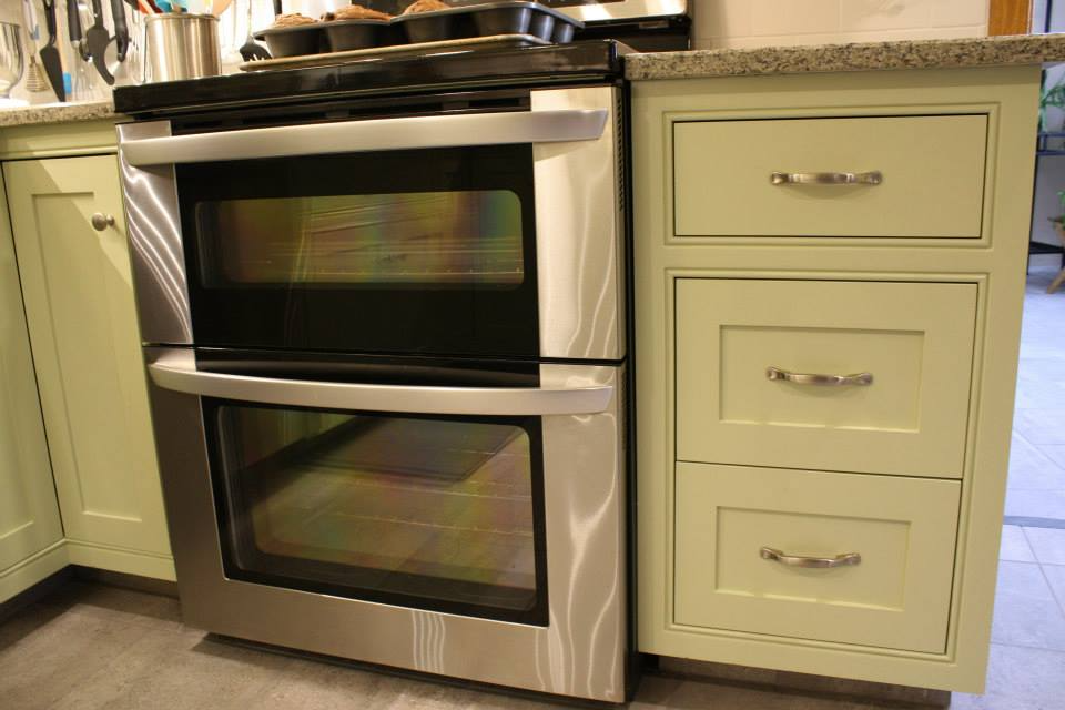 Stainless steel double oven built into green kitchen cabinetry. Granite countertop and drawers.