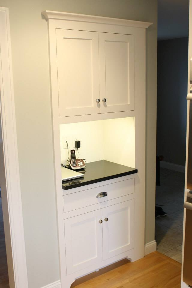 White built-in kitchen cabinet with upper and lower cabinets, a countertop area, and recessed lighting.