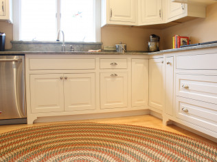 Kitchen with white cabinets, stainless steel appliances, granite countertop, and round rug.